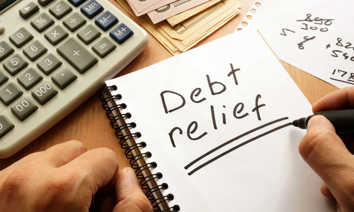 Debt relief written on a notepad sitting on a table with a calculator