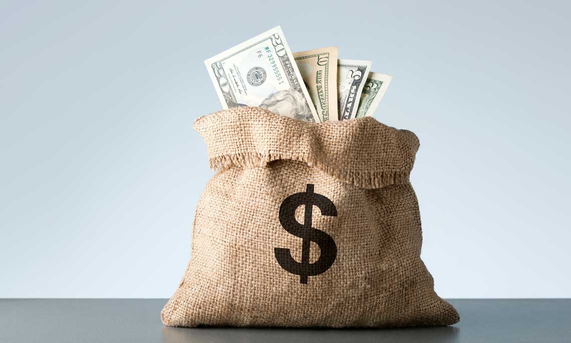 Brown sack of money with dollar sign on bag sitting on table